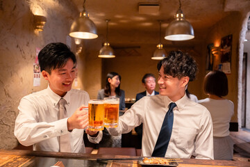 居酒屋でビールを飲む二人の若手ビジネスマン