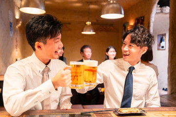 居酒屋でビールを飲む二人の若手ビジネスマン