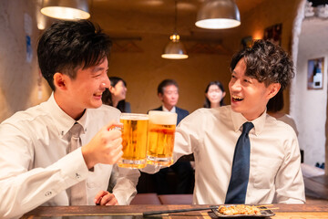 居酒屋でビールを飲む二人の若手ビジネスマン