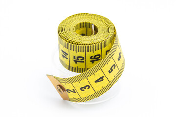 Yellow sewing tape measure rolled up. Plastic packaging on a white background. Tailor's tool for accurate measurements. Fabric measuring tape is essential for fashion design and dressmaking projects