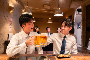 居酒屋でビールを飲む二人の若手ビジネスマン