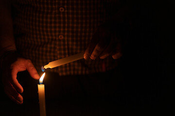 Close up of man's hand lighting a candle in the dark