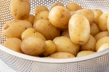 Boiled whole new potatoes in a stainless steel colander strainer utensil