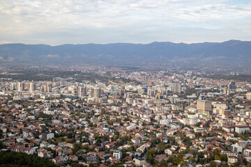 Obraz premium Skopje, a thriving urban panorama The city of Skopje, seen from above Aerial view of the Macedonian capital Skopje, a mosaic of colors and shapes where the mountains meet the metropolis.