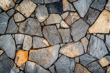 Fototapeta premium An irregular stone wall made of mixed gray and orange stones with a rough texture forming a natural and rustic outdoor pattern 