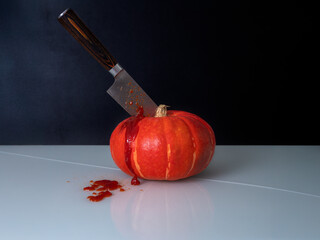 hokkaido pumpkin with a knife stuck in it, dark background, lots of knife, red elements of blood, ketchup, reflection in the base