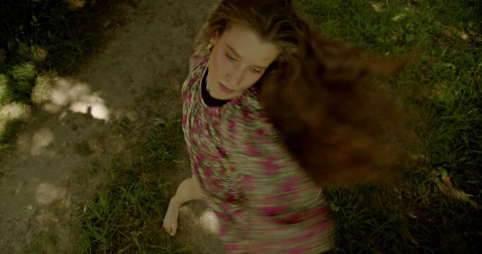 Barefoot girl wearing a floral dress dances interpretive dance in a forest