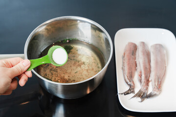 Hand Adding Salt To Brine For Herring Preparation