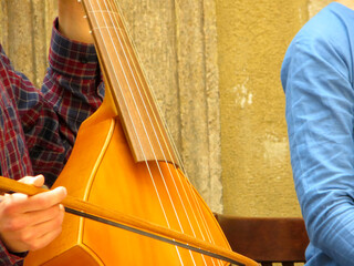 Musician Plays a Viola Da Gamba Using a Bow in a Historical Courtyard During a Sunny Afternoon