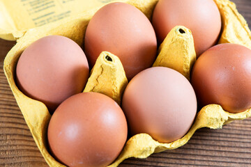Closeup macro of pasture raised farm fresh dozen brown eggs store bought from farmer in carton box...