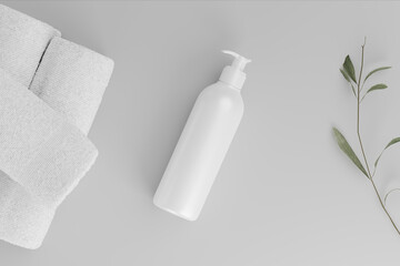 A white bottle with a pump laying on a white surface with a stack of white towels and a green branch