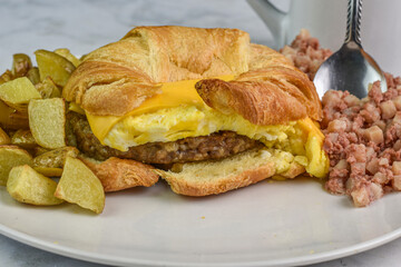 croissant breakfast sandwich  with home fries