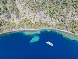 Obraz premium The scenic and rugged coastline of the island of Komba lies 70 km north of the Lesser Sunda Islands of Indonesia. This remote island, surrounded by reef, is an active volcano that often erupts.