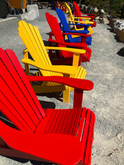 An image of several brightly painted deck chairs lined up in a row with a view of the Pacific Ocean. 