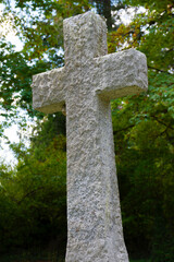 An image of a tall stone cross as a grave marker in an ancient cemetery plot. 