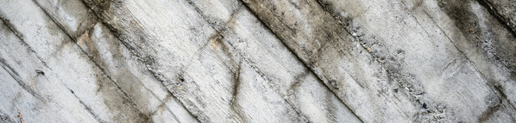 Weathered cement retaining wall with wood grain pattern and texture, wet with algae, as an abstract background
