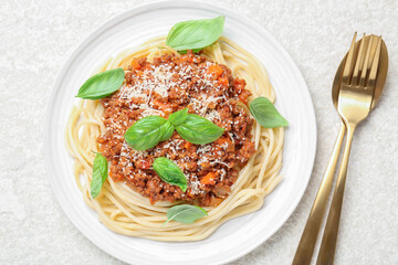 Delicious pasta bolognese and cutlery on white table, flat lay