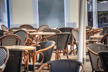 Empty outdoor seating area at a cafe with wicker chairs and tables, showcasing hospitality and catering services.
