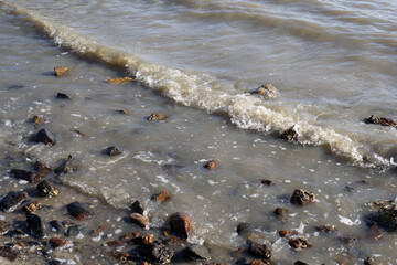Small wave crashing onto a rocky shoreline on a beach