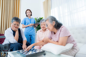 A group of elderly women enjoy a board game together, fostering social interaction and mental stimulation. A healthcare worker stands nearby, ensuring a supportive and healthy environment for senior.