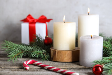 Burning candles, Christmas decor and fir tree branches on wooden table, closeup