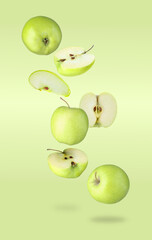 Fresh green apples in air on light green background