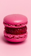 A raspberry macaron with a deep pink shell and tart raspberry filling stands out against a striking fuchsia backdrop.