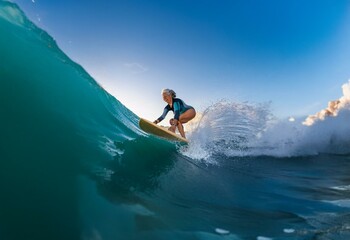 A woman in a wetsuit smiles as she surfs a wave.