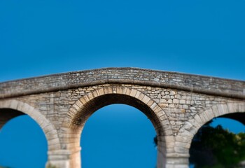 Fototapeta premium A stone arch bridge against a clear blue sky.