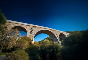 A stone arch bridge against a deep blue sky.