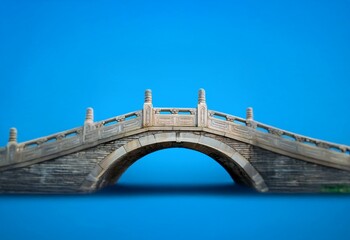 Fototapeta premium A stone arch bridge with intricate carvings against a clear blue sky.