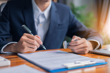 Man carefully reviewed finance agreements and contract documents with his client, discussing loan,...