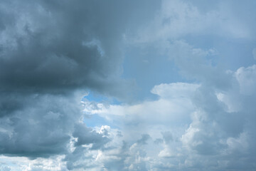 Fluffy white clouds drift across a clear blue sky, casting soft shadows on the Earth