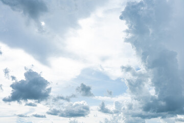 Fluffy white clouds drift across the bright blue sky, casting soft shadows on the lush green landscape