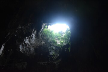 stalagmites and stalactites with sunlight through cave hole in Khao Luang cave travel location on Thailand