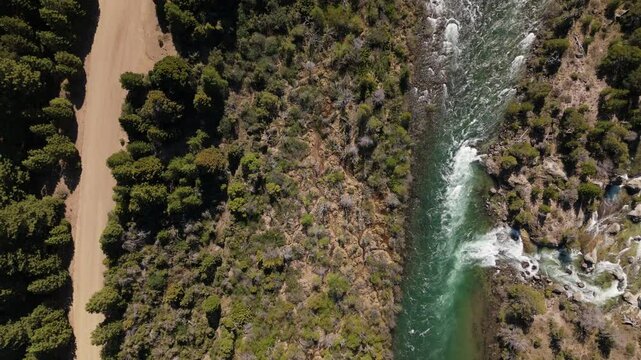 Aerial shot of the Caleuf&uacute; River winding through the lush pine forests in Villa Meliquina, Argentina. The landscape is dominated by vast green forests, including pines, coihue, and lenga trees.