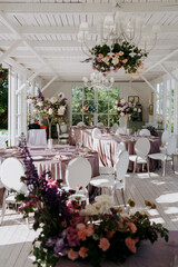 In a large room, there are several tables and chairs arranged thoughtfully, and prominently displayed on one of the tables is a lovely vase of flowers