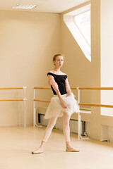 Focused ballet dancer stands with hand on tutu
