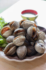 Cooked cockle on plate usually serve with spicy seafood sauce, menu from sea shell. Semi-cooked raw food.