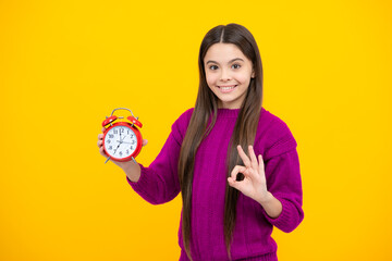 Teen student girl with clock isolated on yellow background. Child back to school. Education and time concept.