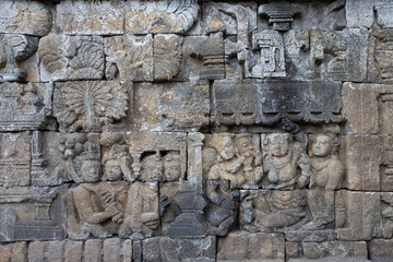 Stone wall with old religious statues craved in Borobudur Temple in Indonesia