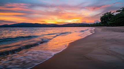 Obraz premium Calm sunrise over an empty beach with gentle waves lapping at the shoreline and a colorful sky reflecting off the water