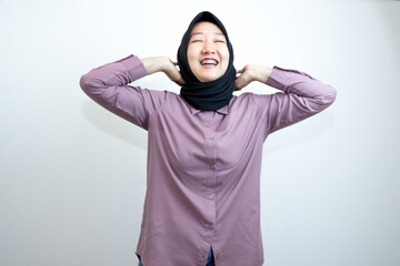 Portrait of emotional Indonesian woman laughing and wearing a purple shirt and black headscarf is laughing while pointing with her hands. isolated on white background