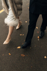 A bride and groom are happily walking hand in hand down the sunny street, celebrating their joyous day together with smiles