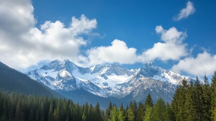Obraz premium Breathtaking view of snow-capped mountains under a clear blue sky, surrounded by lush evergreen forests and scattered clouds.