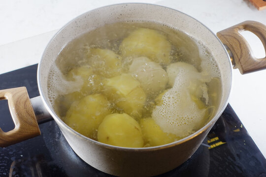 Potatoes are currently boiling in a pot placed on the stove, ready for a delicious meal