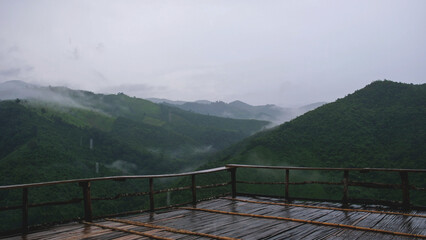 Naklejka premium Landscape of greenery rainforest and hills outside wooden terrace on raining day