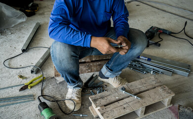 A builder works with screws and nuts on a wooden pallet