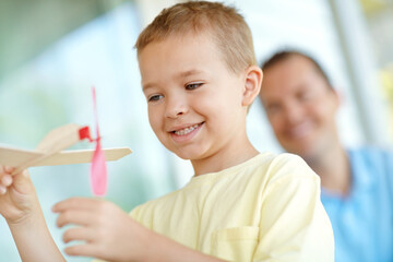 Toys, airplane and boy child with dad, smile and playful fun on patio together for creative morning bonding. Playing, weekend games and happy kid on porch with model plane, father and son in home