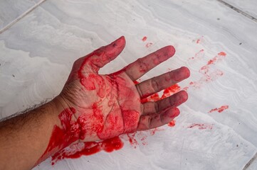 A bloody hand lying on a dark floor, symbolizing violence or despair © Anzz Stock